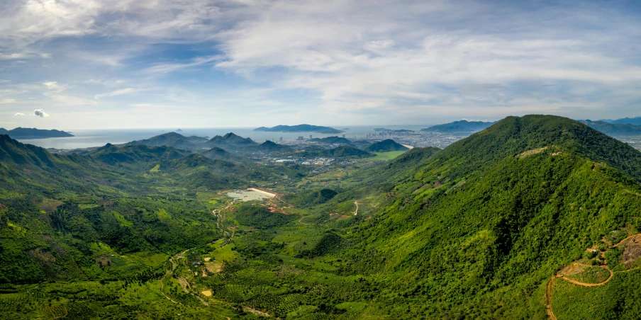 large green mountains covered in trees under a blue sky