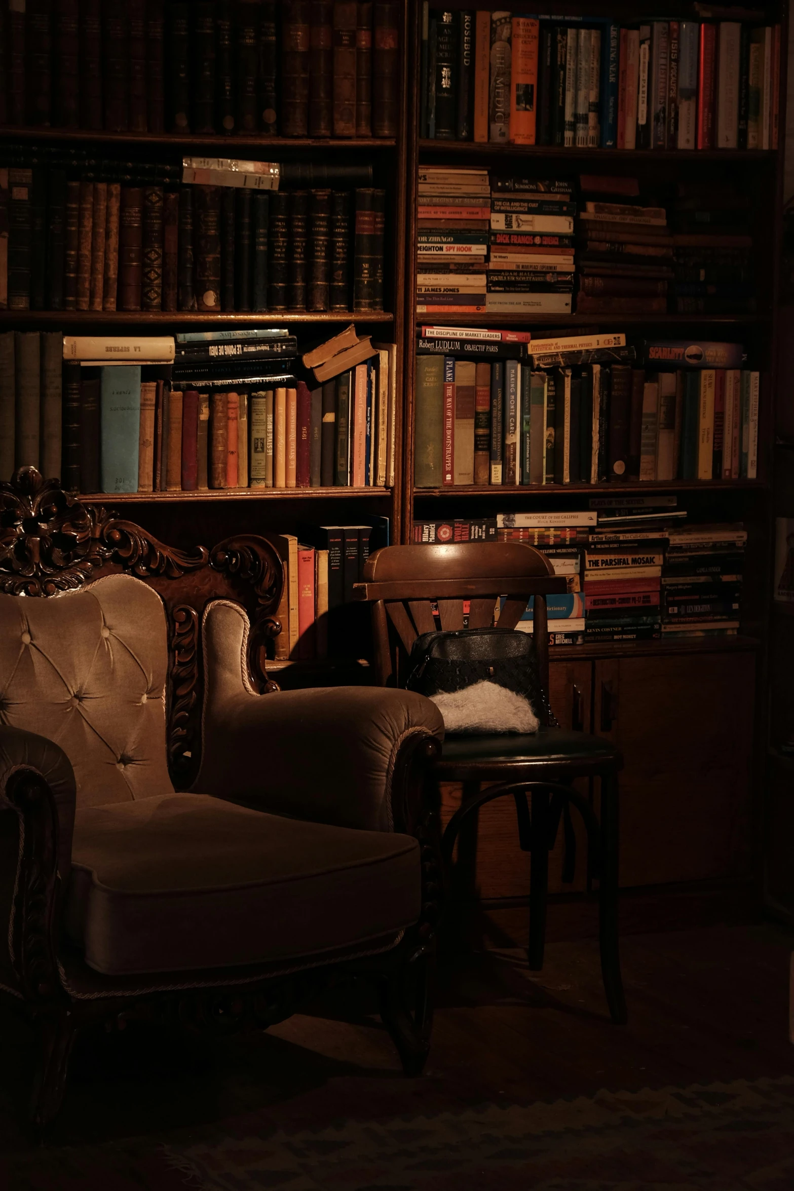 a dimly lit room with a chair and a large bookcase