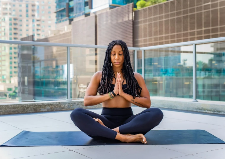 a woman doing yoga poses on a roof in a black top and pants