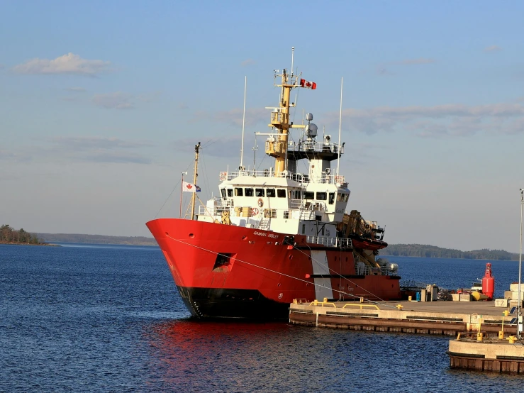 a red and white ship docked at a pier