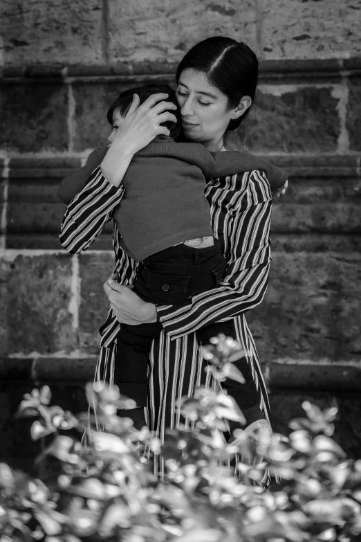 a woman holding a child near a wall