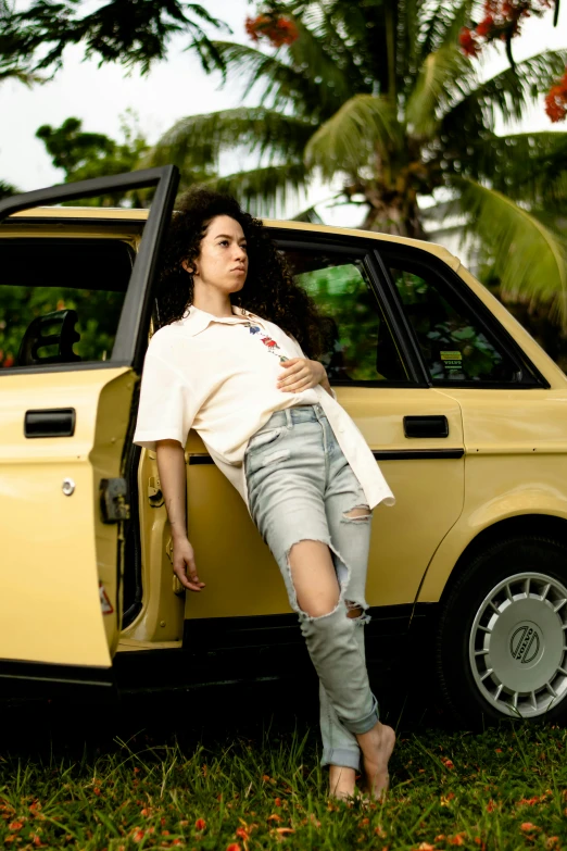 a woman leaning out of an old yellow car