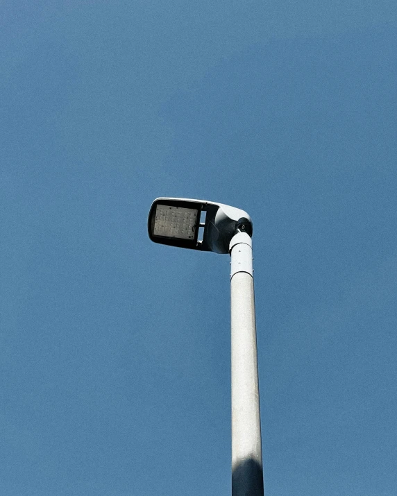 street light turned on under a bright blue sky