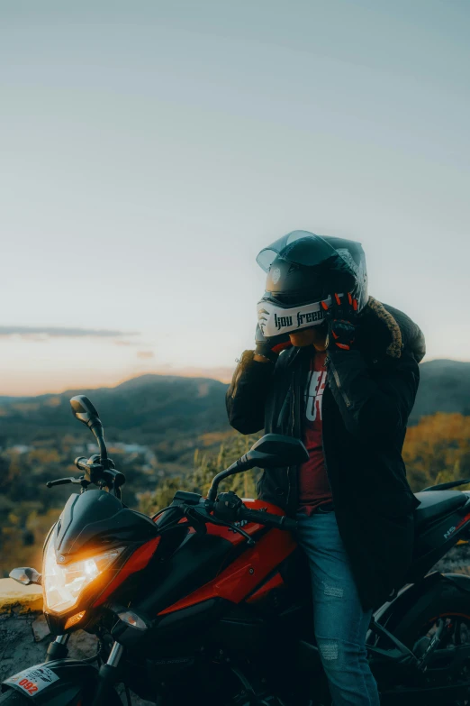 a man sits on his motorcycle as the sun sets