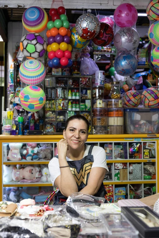 a woman sitting in front of a counter with lots of stuff behind her