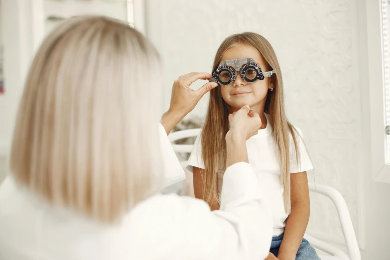 a little girl wearing sunglasses looking at a woman's reflection in a mirror