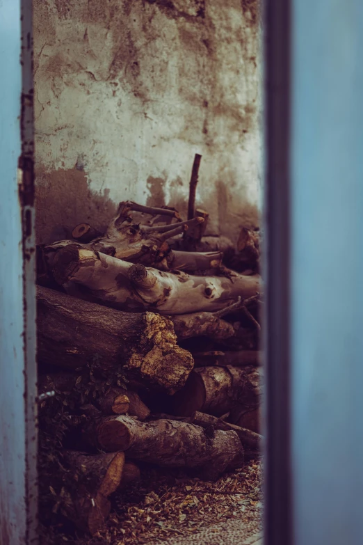 a pile of wooden logs sitting next to a wall