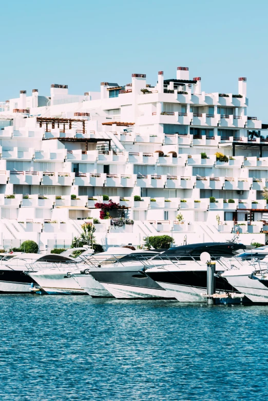 boats lined up along a dock near a tall building