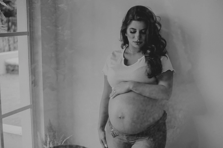 a pregnant woman standing with her arms wrapped around the edge of her stomach