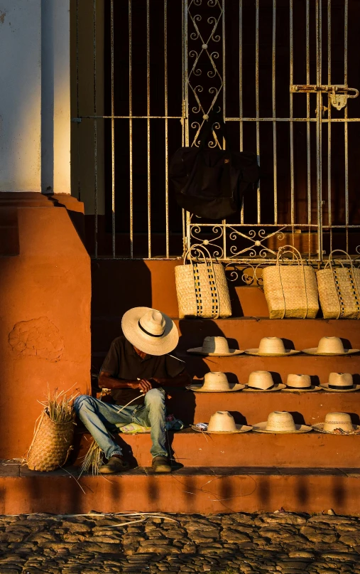 a man is sitting on the steps with his hat on