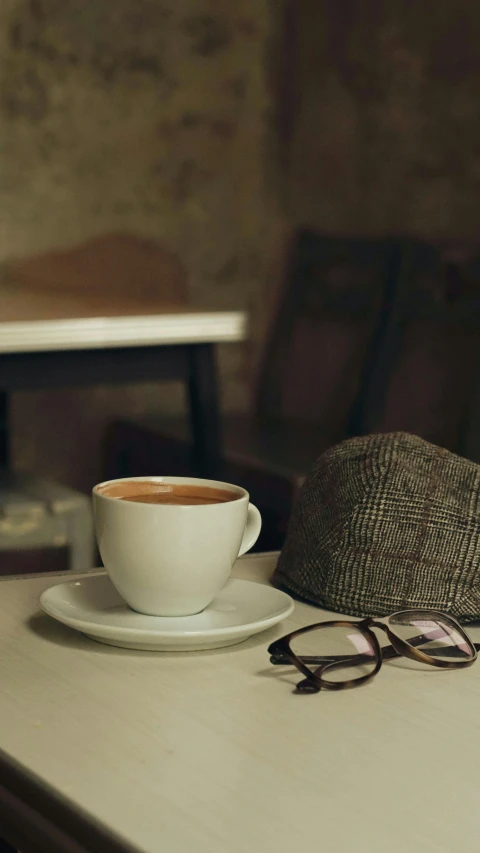 a cap on top of a table next to a cup and glasses