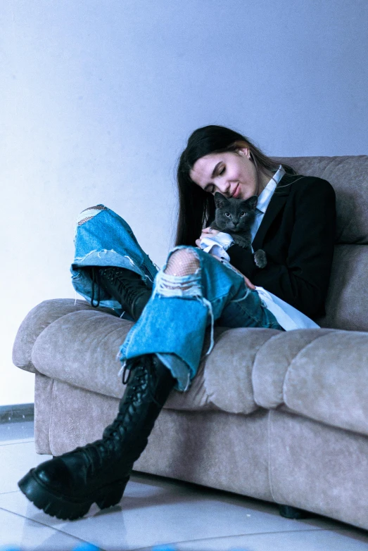 the woman sits on a couch with her cat