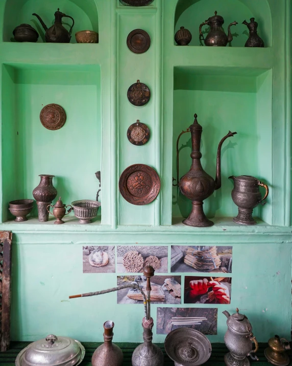 a green room with an arrangement of different dishes and vases