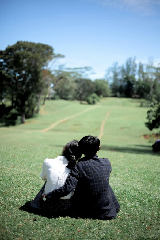 the man is holding his little boy in the grass