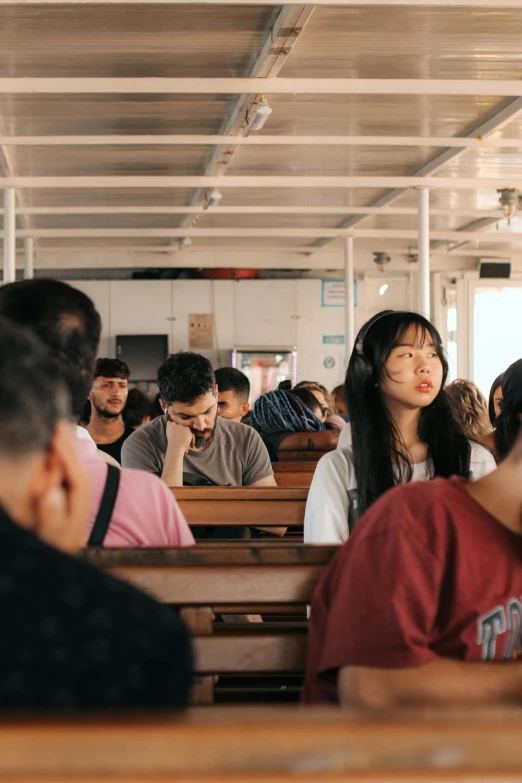 a large group of people sitting in small wooden benches