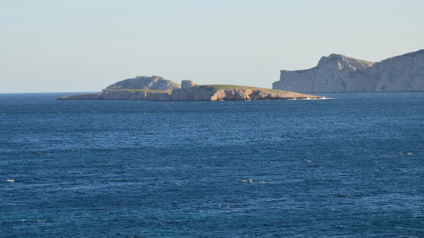 an ocean scene with several large rocks in the background