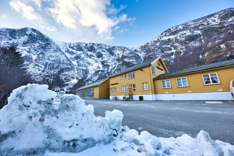 a yellow building next to some snow covered mountains