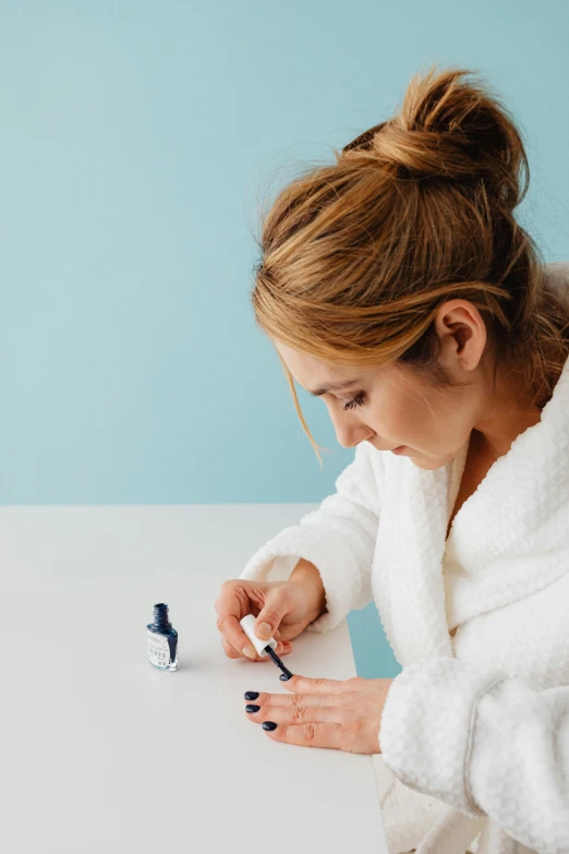 a woman holding a nail brush and putting it on another bottle