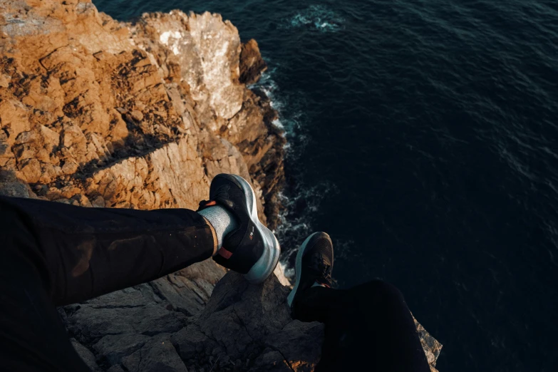 feet touching the cliffs by the ocean from a walkway