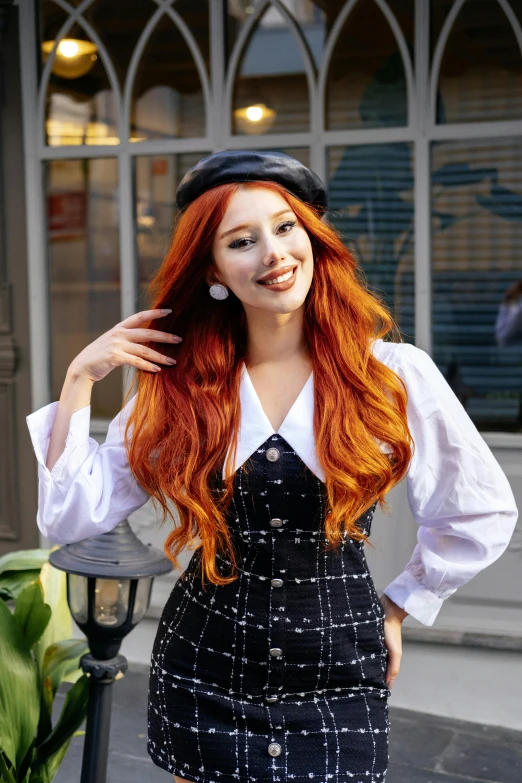 a woman with red hair is posing in front of a building