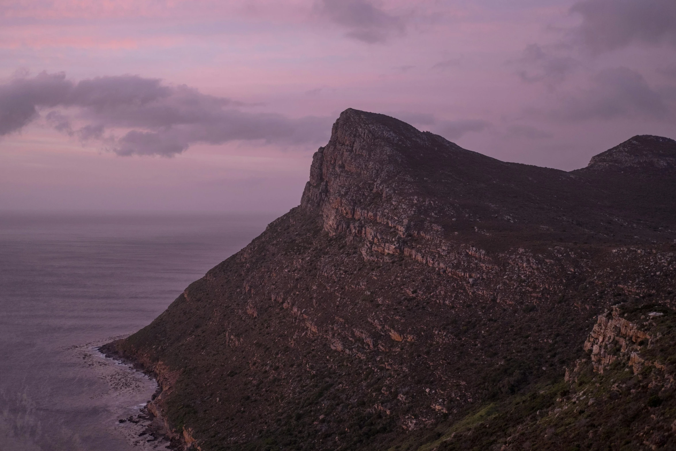 clouds gather over a rocky coastline on a hazy day