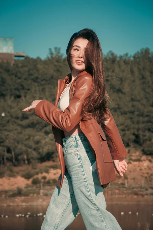 a woman walking while holding onto a leather jacket