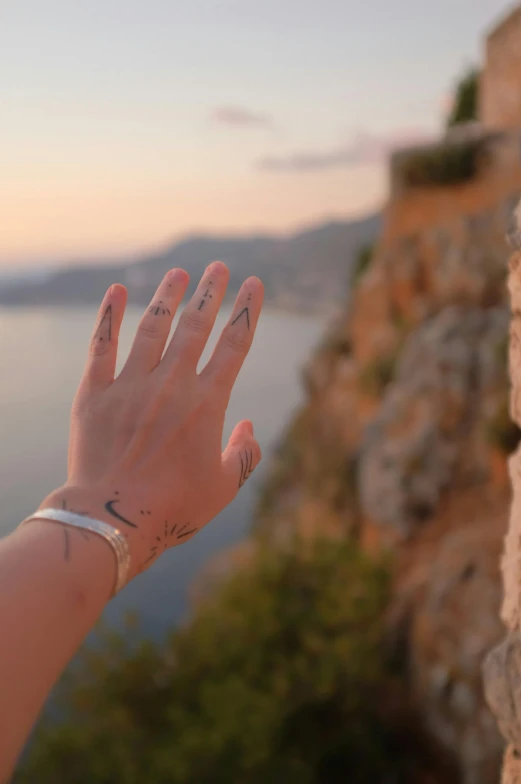 the hand with tattoos is reaching out towards the ocean