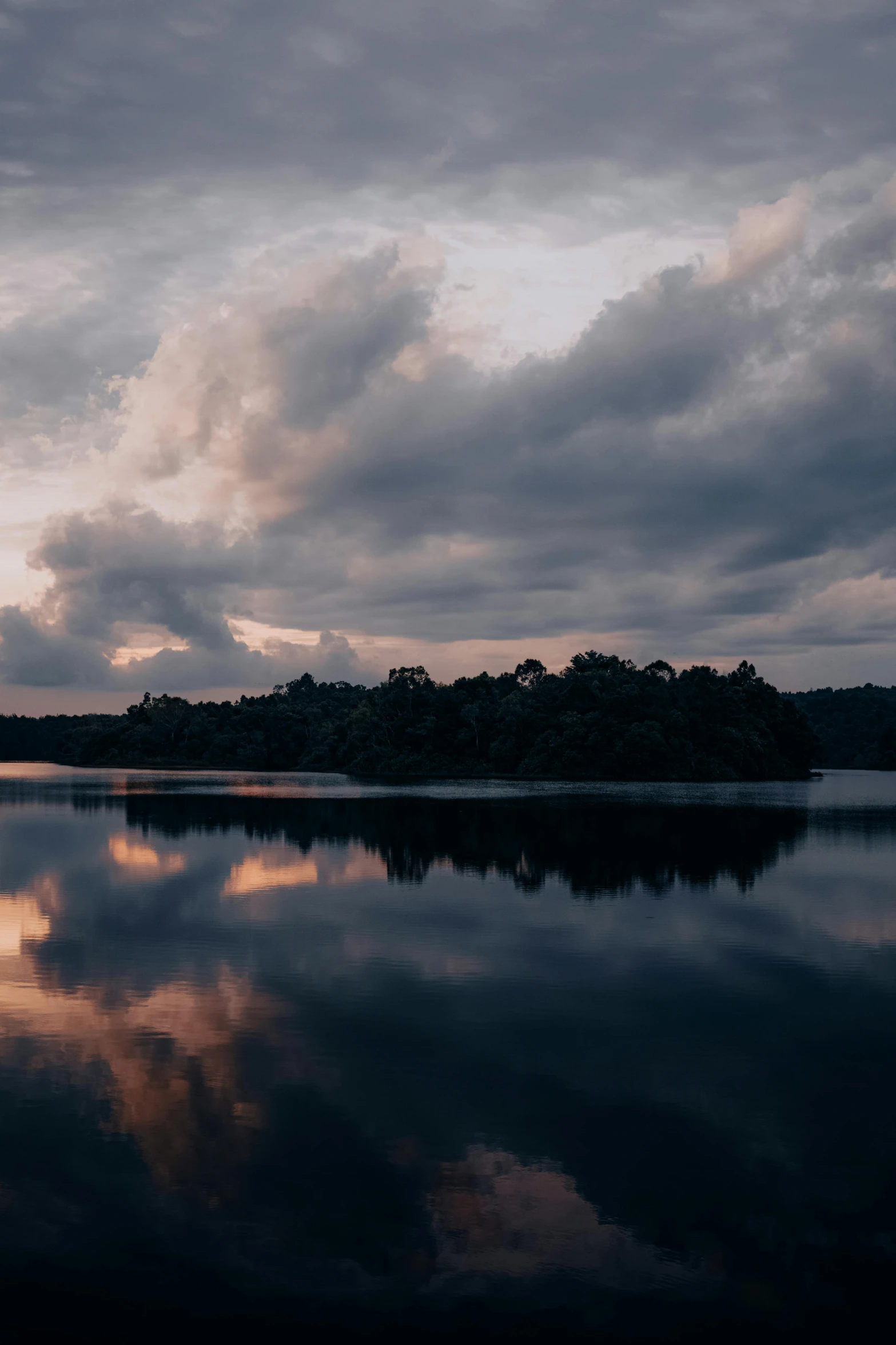 an empty body of water surrounded by trees and clouds