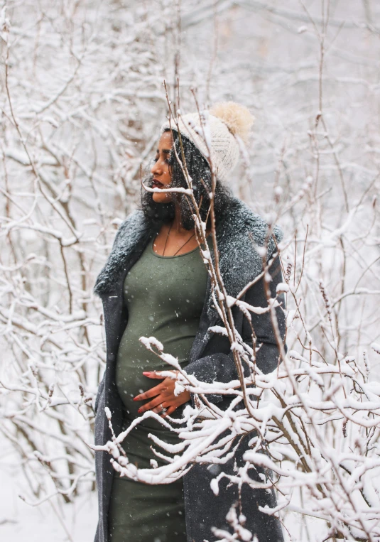 pregnant woman in snowy winter forest with snowflakes