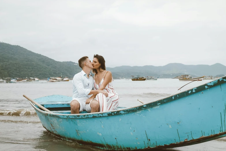 a woman kisses a man in a blue boat in the water