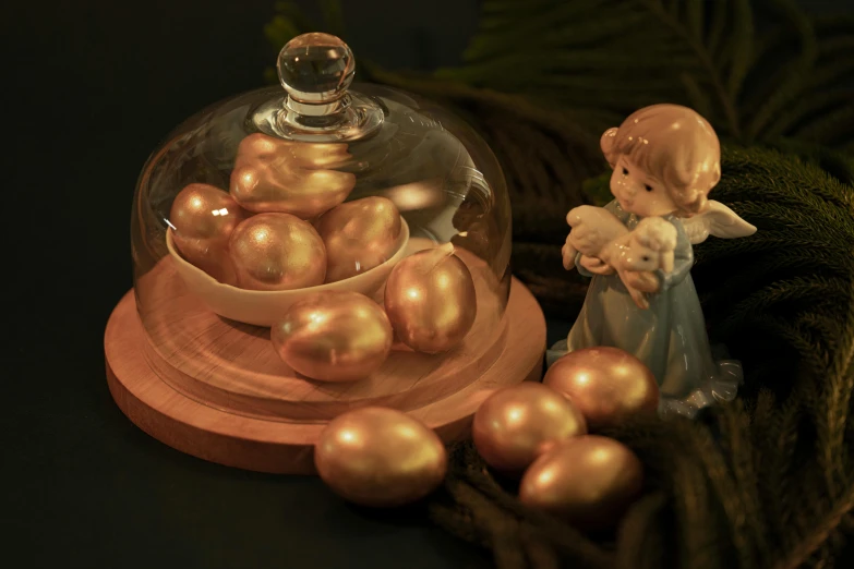 a small angel figurine is next to a clochet of golden eggs