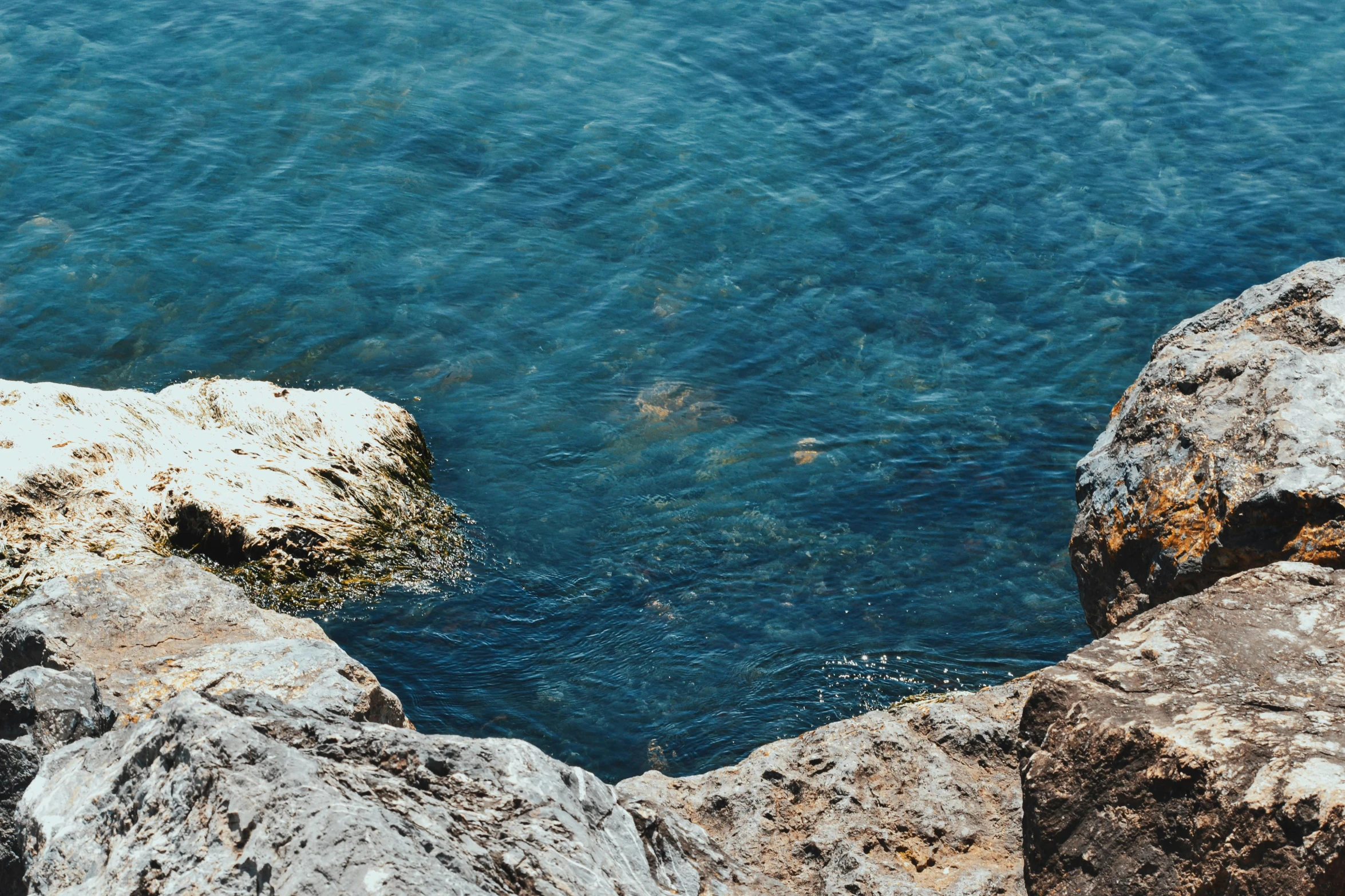 rocks at the edge of a calm blue water