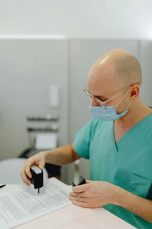 a man wearing a surgical mask and glasses working with some type of equipment