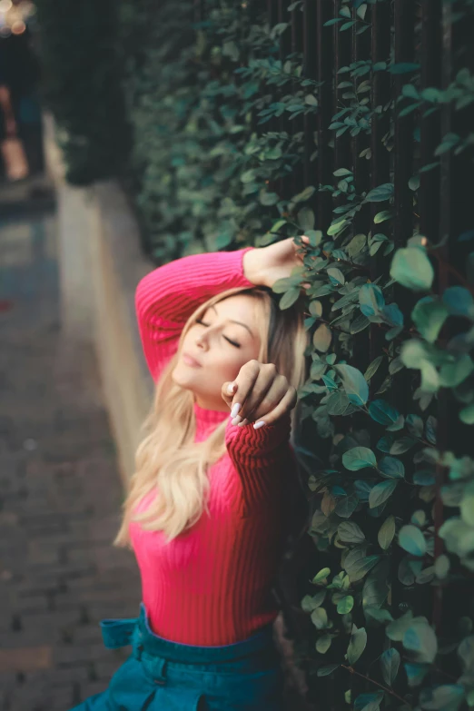 a woman leaning against a fence talking on her cell phone