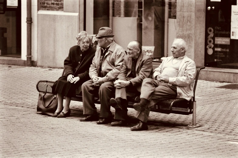 black and white pograph of three men and a woman sitting on a bench