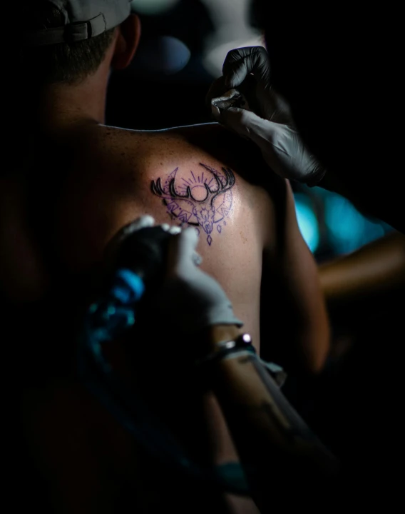 a man with his hand on his shoulder is looking at his watch and tattoos