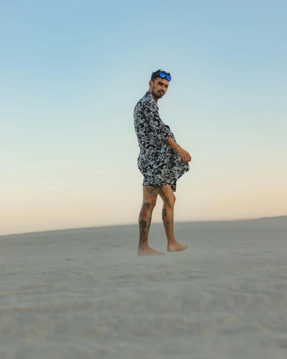 a man stands on sand, holding his hands together