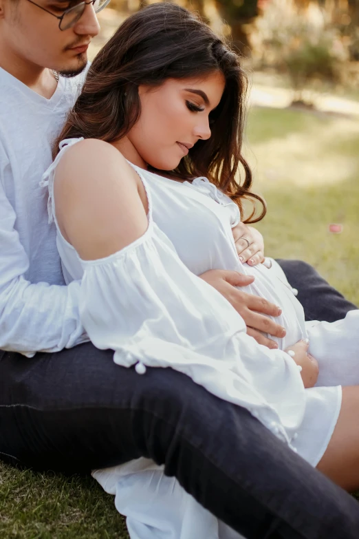 man and woman holding child on grassy field