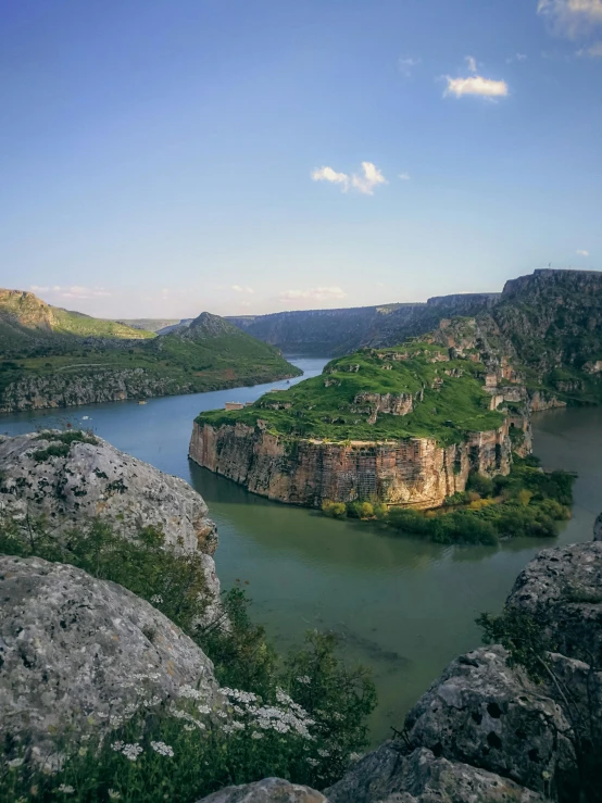 a lake surrounded by cliffs with trees and bushes on the sides