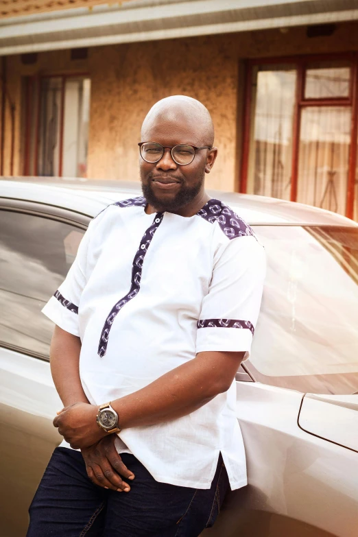 a man in a white shirt leaning on the door of a car