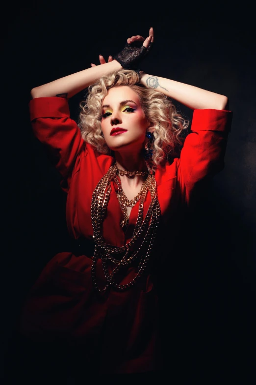 a woman is sitting in a black room and wearing a red shirt