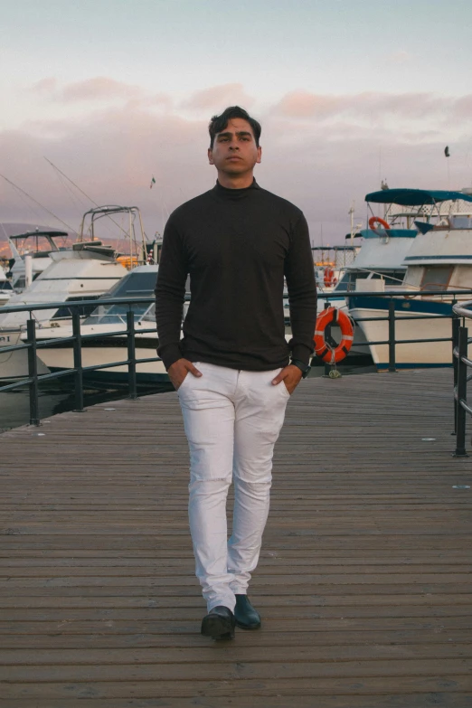 a man standing on a wooden pier next to boats