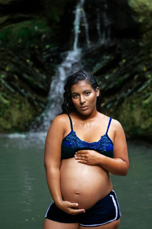 a woman wearing a bikini next to a waterfall