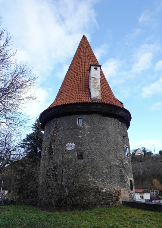 a stone tower with a clock and red tile on the roof