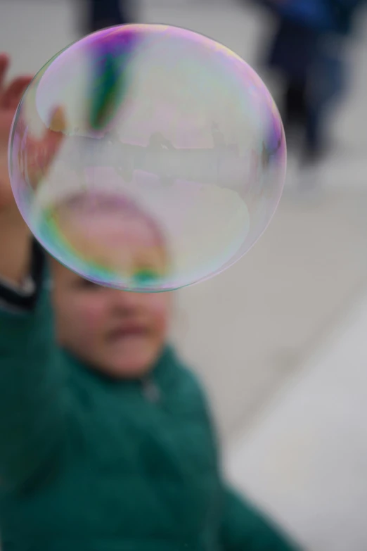 a boy who is holding up a soap bubble