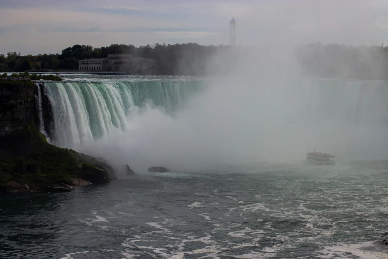 a boat in front of a waterfall in the water