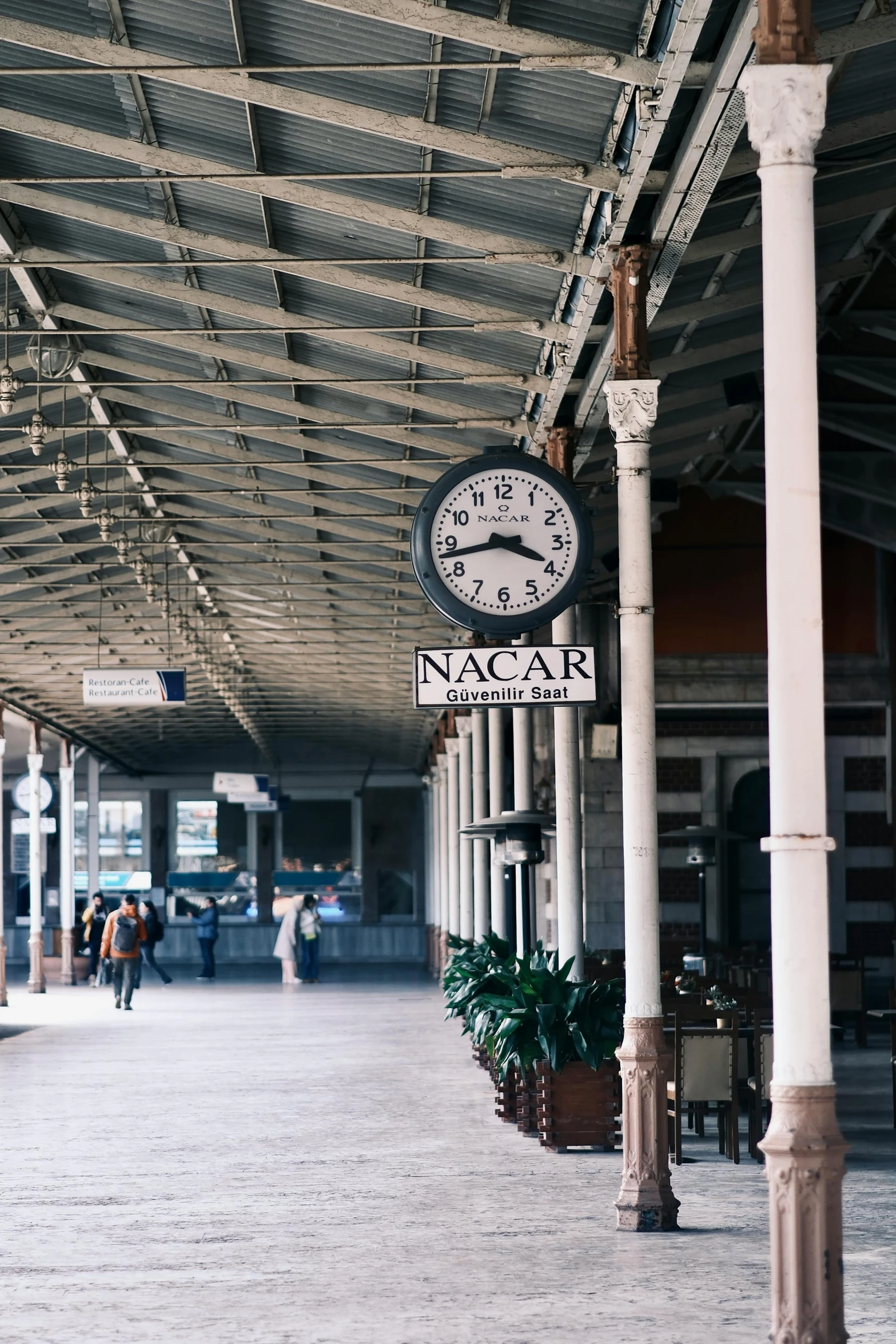 a clock stands in the middle of a railway station