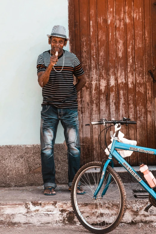 man with black and white shirt next to blue bicycle