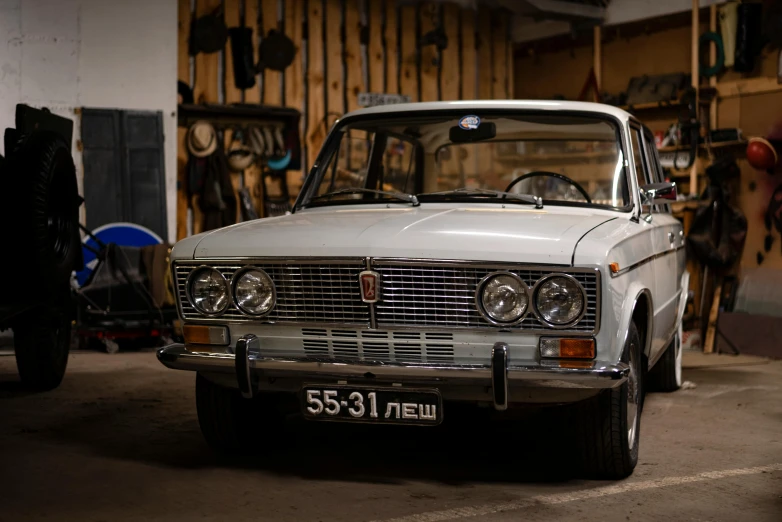 a white car in a garage surrounded by wooden pallets