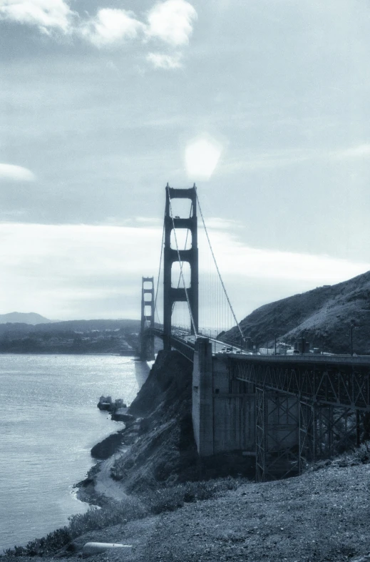 a bridge sits over the water that runs from a beach to a hill